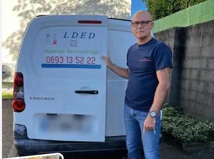 Appliance repair professional beside an LDED van